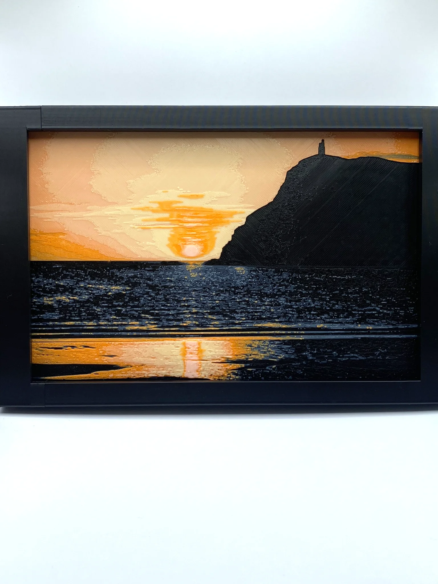A filament painting showing the sun setting behind Bradda head, with a fully view of port erin bay and the sun's reflections